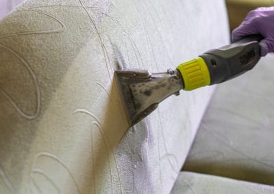 Closeup of upholstered Sofa chemical cleaning with professional extraction method. man hands in rubber gloves hold hoover nozzle